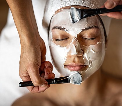 Frau bekommt eine Gesichtsmaske aufgetragen
