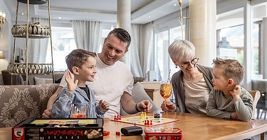 Familie spielt in Hotelhalle Mensch ärgere dich nicht