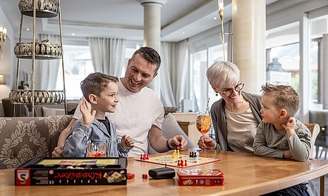 Familie spielt in Hotelhalle Mensch ärgere dich nicht