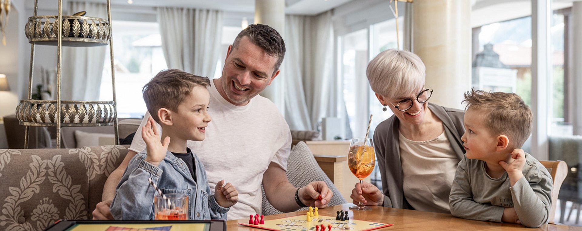 Familie spielt in Hotelhalle Mensch ärgere dich nicht