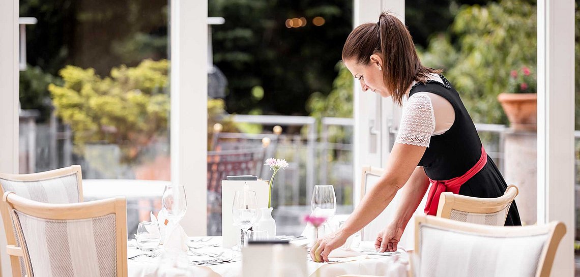 Servicekraft deckt Tisch im Hotel