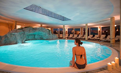 Frau sitzt am Beckenrand vom Pool