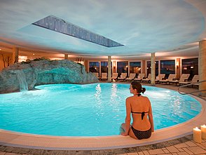 Frau sitzt am Beckenrand vom Pool