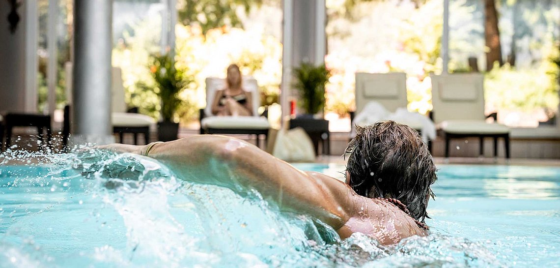 Mann schwimmt im Hallenbad