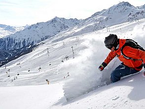 Skifahrer bei der Abfahrt im Tiefschnee