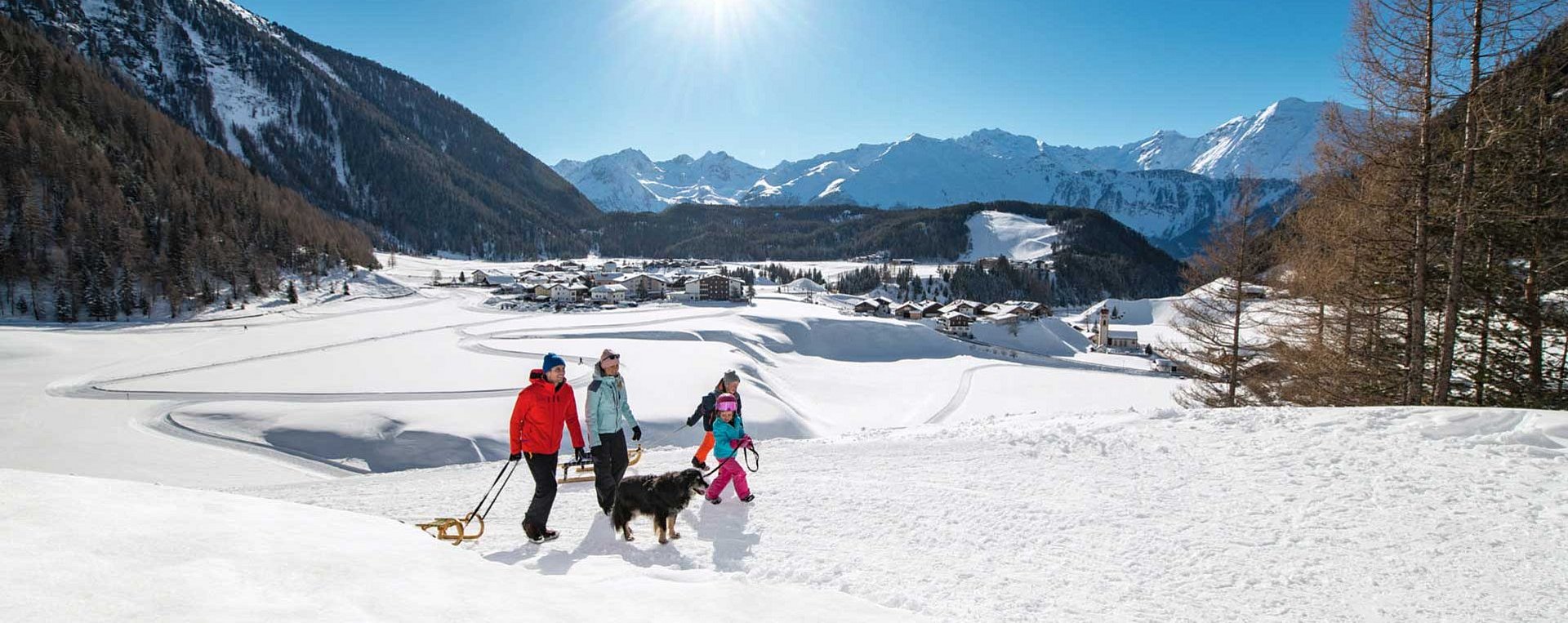 Familie beim Spaziergang mit der Rodel