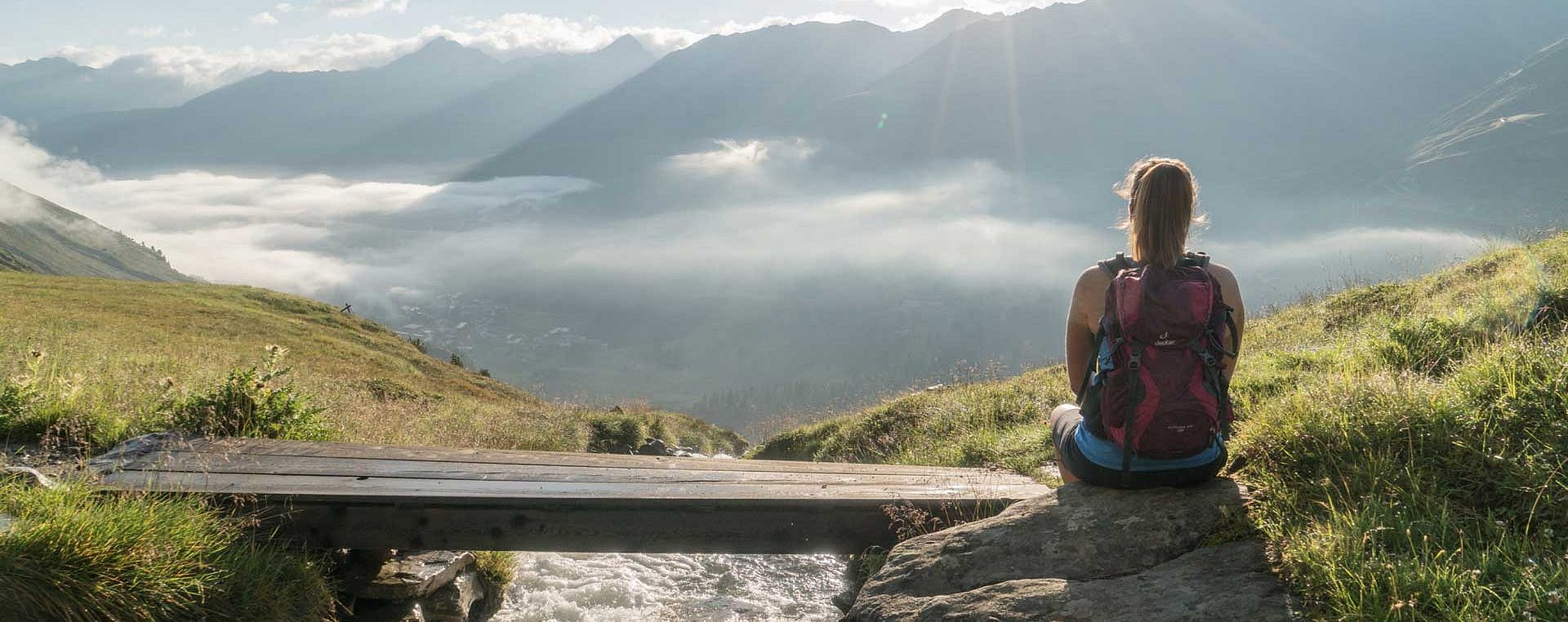 Wanderer sitzt am Steg vor Bergpanorama