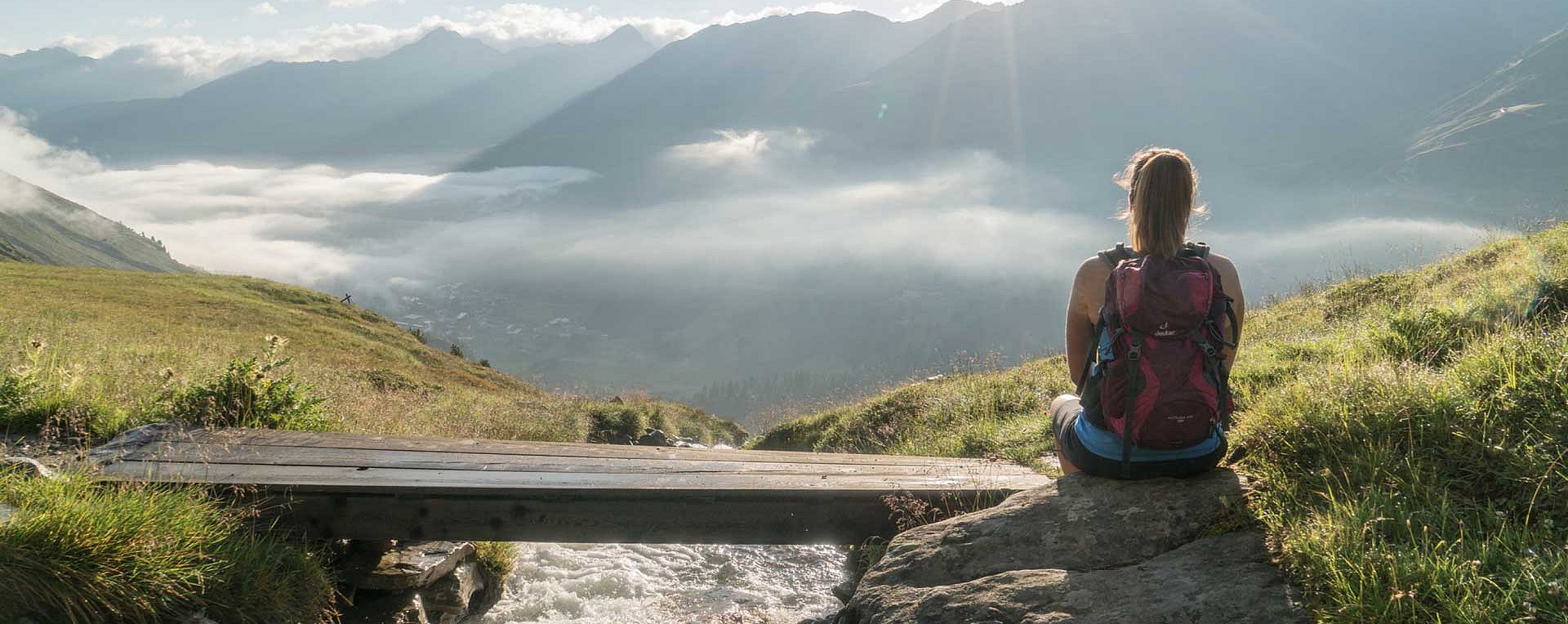 Wanderer sitzt am Steg vor Bergpanorama